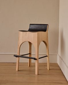 a wooden stool sitting on top of a hard wood floor next to a white wall