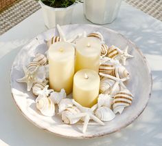 three candles are sitting on a plate with seashells and starfish around it