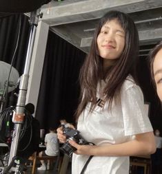 two young women standing next to each other holding camera equipment in front of a microphone