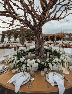 the table is set with white flowers, candles and napkins for an elegant dinner