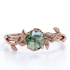 a ring with an oval green stone in the center and leaves on each side, surrounded by diamonds