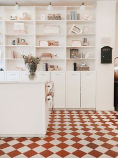 a white kitchen with checkered flooring and shelves full of books on the wall