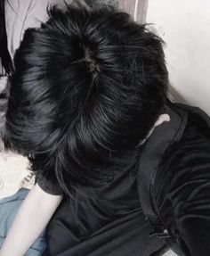 a person with black hair is laying on the floor and looking at something off to the side