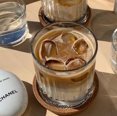 an iced drink with ice sits on a table next to two glasses and a ball