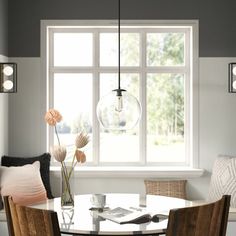 a dining room table with four chairs and a vase filled with flowers in front of a window