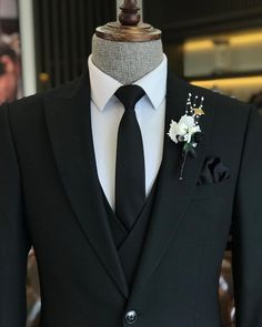 a black suit with a white flower on the lapel