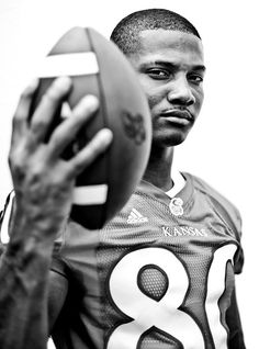 a black and white photo of a football player holding a ball in his right hand