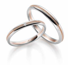 two white and rose gold wedding rings with diamond in the center on a white background