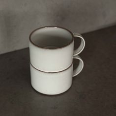 two white coffee cups sitting on top of a table