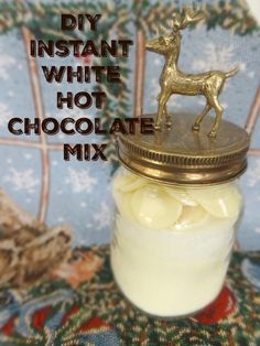 a glass jar filled with white hot chocolates next to a gold deer figurine