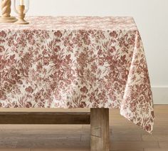 a table with a red and white floral design on it, next to two candles