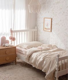 a white bed sitting in a bedroom next to a window with curtains on the windowsill