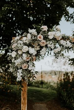 a wooden arch decorated with white flowers and greenery for an outdoor wedding in the countryside