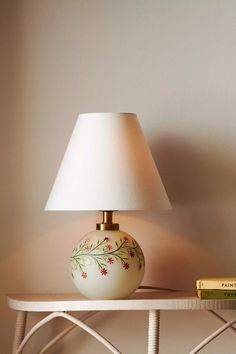 a lamp sitting on top of a white table next to a book and some books