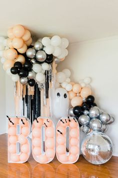 balloons and letters spelling boo on a table in front of a wall with halloween decorations