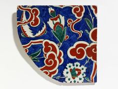 a blue and red plate with floral designs on the front, sitting on a white surface