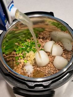 the food is being cooked in the pot on the stove top, with water pouring into it