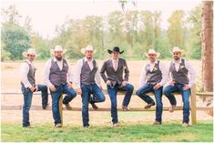 a group of men sitting on top of a wooden bench wearing cowboy hats and vests