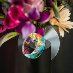 a vase filled with purple and pink flowers on top of a black table next to a metal stand