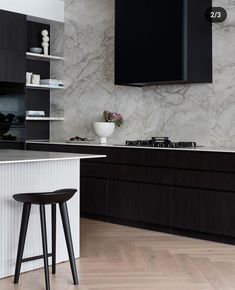 a black and white kitchen with marble countertops, dark wood cabinets and stools