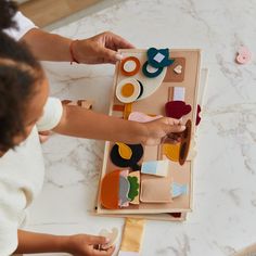 two children are playing with wooden toys on the floor in front of a marble table