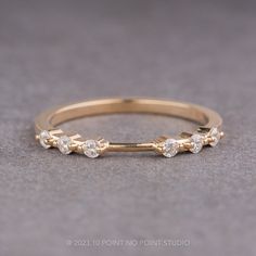 a yellow gold ring with three diamonds on the side, sitting on a gray surface