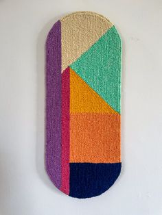 a multicolored wall hanging on the side of a white wall