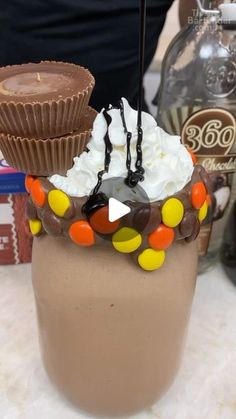 there is a cupcake on top of a chocolate drink with whipped cream and candy