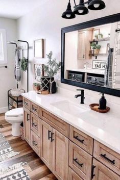 a bathroom with wooden cabinets and white counter tops, black accents on the mirror over the sink