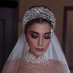 a woman in a wedding dress wearing a veil and tiara with jewels on it