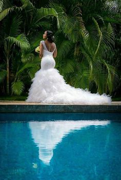 a woman in a wedding dress standing next to a pool