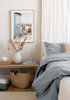 a bedroom with white walls and blue linens on the bed, along with a wicker basket