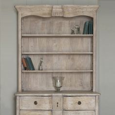 an old white bookcase with drawers and vases