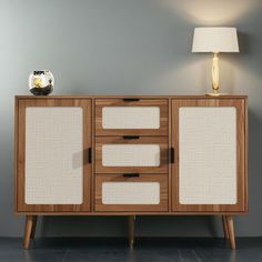 a sideboard with two doors and three drawers on the bottom, in front of a gray wall