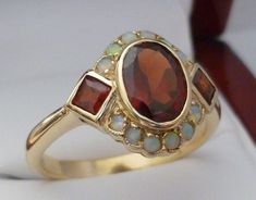 This STUNNING Victorian Garnet & Opal ring has been majestically crafted from 9ct Solid Gold with reference to a vintage design. A bezel set HUGE Oval cut NATURAL Garnet brings this ring to life along with two Vibrant Square cut NATURAL Garnets resting on the shoulders adding additional appeal to this exquisitely feminine ring. Surrounding the face of this GORGEOUS ring are accentuating GENUINE Australian Opals which have been magnificently inset adding fire and exotic appeal to any lady who Vintage Garnet Ring, Garnet Ring Gold, Garnet Ring Vintage, Ruby Ring Vintage, Opal Ring Vintage, Womens Ring, Opal Ring Gold, Victorian Rings, Garnet Jewelry