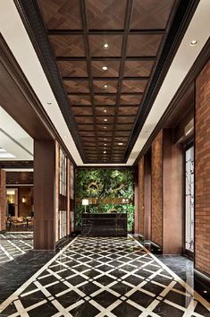 an elegant lobby with black and white tile flooring, large windows and plants on the wall