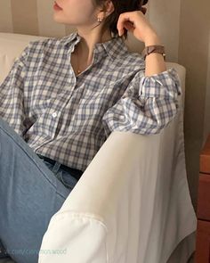 a woman sitting on top of a couch with her hand in her hair and looking off to the side