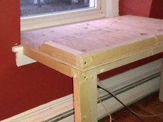 a wooden table sitting in front of a window next to a radiator and power cord