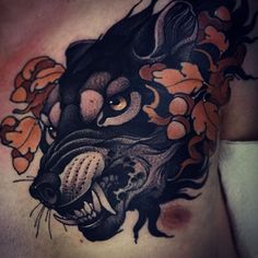 a man's chest with a black and orange tattoo design on it, featuring an animal