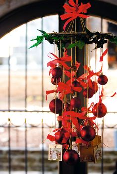 a wind chime with ornaments hanging from it's sides and red bows on the top