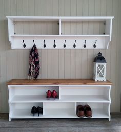 a white bench with shoes on it next to a wall mounted coat rack and shelf