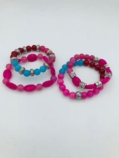 "Set of 4 mixed pink and blue agate stretch bracelets. The bracelets measure 7\" - 7 1/4\" and are made of smooth round 8mm stones and hot pink faceted oval shaped stones that measure 10x13mm.  Bracelet 1 features 5 blue calcite beads, 5 red beads and 5 pink beads separated by silver plated spacer beads.  Bracelet 2 features 8 hot pink oval shaped agate beads alternating with 8 round pink calcite beads.  Bracelet 3 features 5 blue calcite beads, 5 red beads and 10 pink beads. There is a silver p Pink Adjustable Stretch Bracelet With Natural Stones, Adjustable Pink Stretch Bracelet With Natural Stones, Pink Natural Stones Round Stretch Bracelet, Pink Natural Stone Stretch Bracelet, Pink Natural Stones Stretch Bracelet, Adjustable Pink Stretch Bracelet With Gemstone Beads, Adjustable Pink Gemstone Bead Stretch Bracelet, Pink Stretch Bracelet With Natural Stones, Pink Stackable Stretch Bracelet With Round Beads