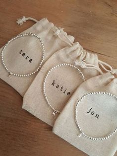 three personalized bracelets with names on them sitting next to a drawstring bag