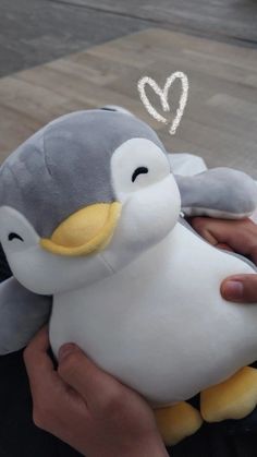 a person holding a stuffed penguin in their hands