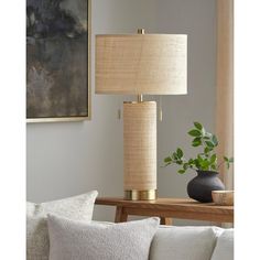 a lamp that is on top of a table next to a vase with a plant in it