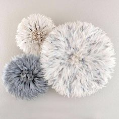 three white and gray pom - poms hanging on the wall