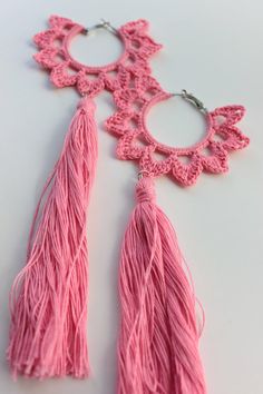 a pair of pink tasselled earrings sitting on top of a white table next to each other