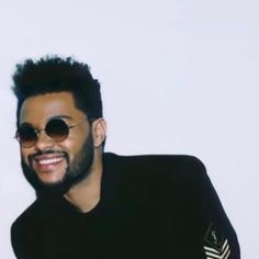 a man in black shirt and sunglasses smiling