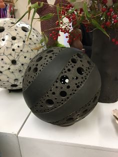 three decorative vases sitting on top of a white counter next to plants and flowers