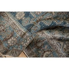 an old rug with blue and brown colors on the floor in front of a wooden table